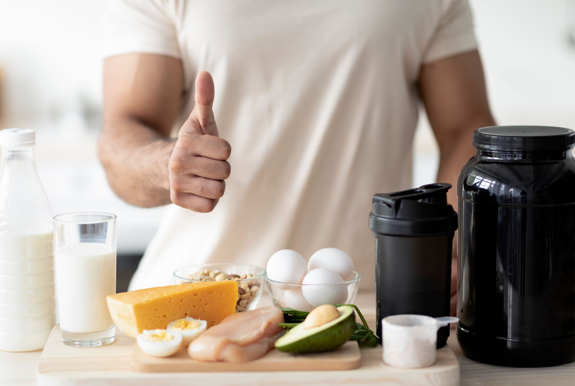 Unrecognizable sporty man showing thumb up, recommending healthy nutrition for muscle gain or weight loss at kitchen