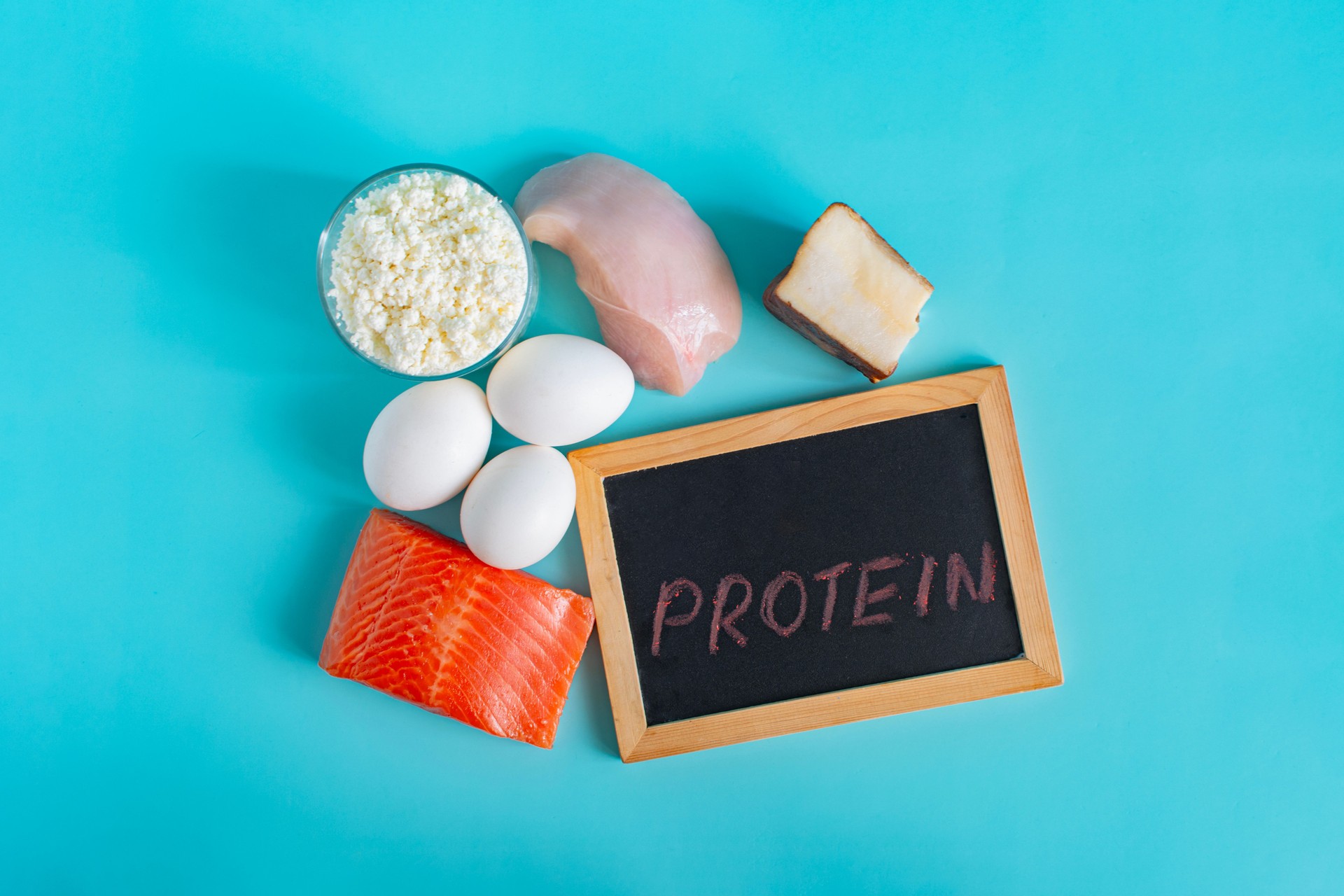 A set of different high-protein foods on a light background with a close-up inscription "protein"