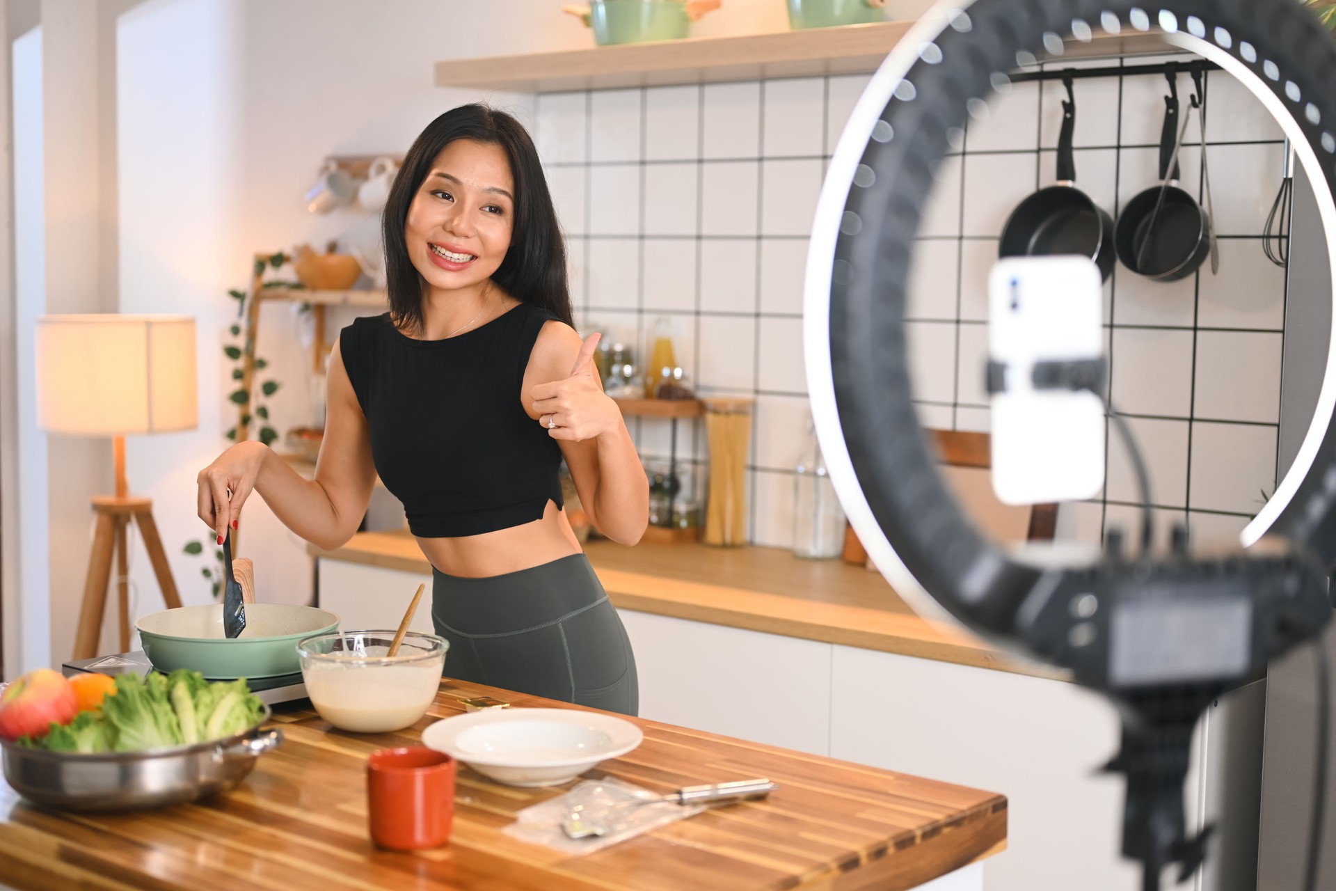 Cheerful millennial woman recording a cooking tutorial in a modern kitchen